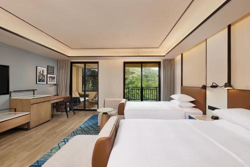 um quarto de hotel com duas camas e uma televisão em Four Points by Sheraton Hainan, Qiongzhong em Qiongzhong