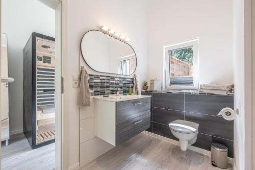 a bathroom with a sink and a toilet and a mirror at Neues Ferienhaus an der Ostsee+Terrasse+Sauna in Surendorf