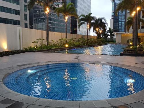 a large blue pool with palm trees and buildings at RENTZONE88 in Manila