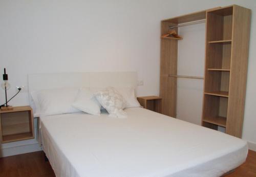 a bed with white sheets and pillows in a room at Antich Apartment Deltebre in Deltebre