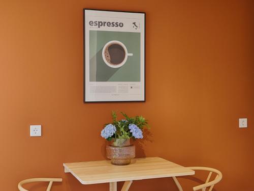 a table with a vase of flowers and a picture at homie stay Badgasse - Fewos am Main mit Dachterrasse & Fahrradgarage in Ochsenfurt