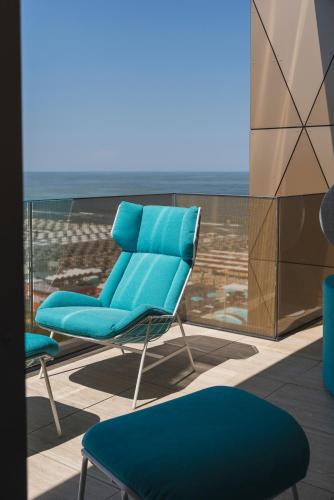 a blue chair on a balcony with a view at The Promenade Luxury Wellness Hotel in Riccione