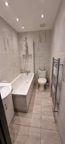 a bathroom with a tub and a toilet and a sink at Modern 2 BDR apartment in London