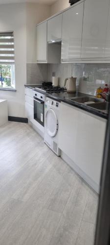 cocina con armarios blancos y lavavajillas en Modern 2 BDR apartment en Londres