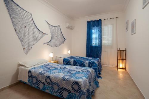 2 letti in una camera con blu e bianco di Villa Cecilia a Sciacca