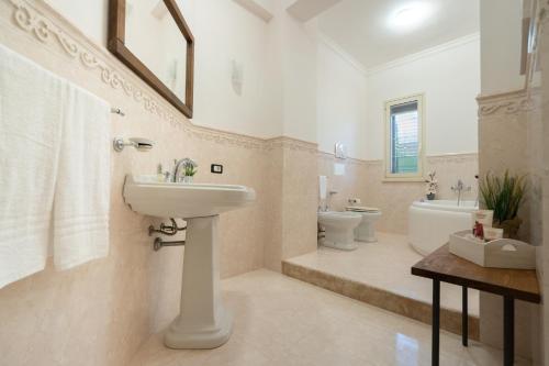 bagno bianco con lavandino e servizi igienici di Villa Cecilia a Sciacca