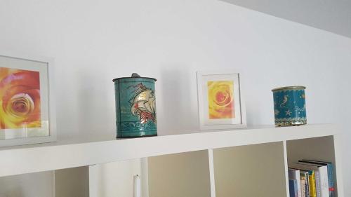 three vases sitting on a shelf with paintings at Ferienwohnung Mueller_ 15121 in Leer