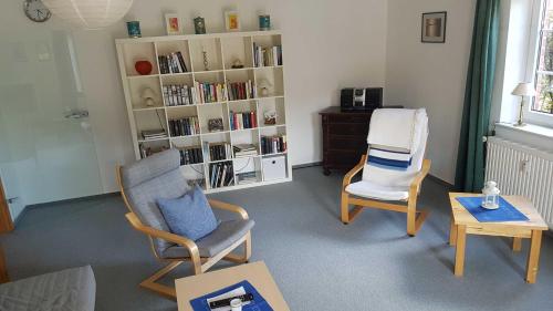 a living room with two chairs and a book shelf at Ferienwohnung Mueller_ 15121 in Leer