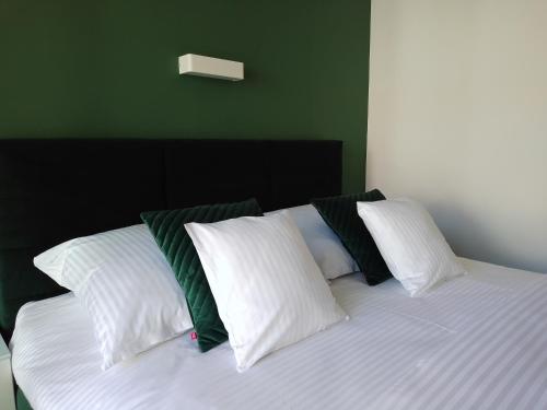 a bed with white and green pillows on it at Apartamenty Mistral in Jastarnia