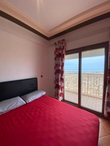 una camera con un letto rosso e una grande finestra di Appartement Sidi Bouzid a El Jadida