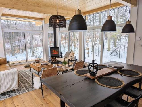a living room with a table and chairs and windows at trähus tremblant in La Conception
