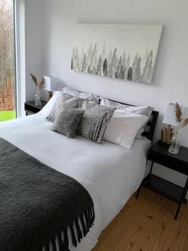 a bedroom with a large white bed with two night stands at trähus tremblant in La Conception