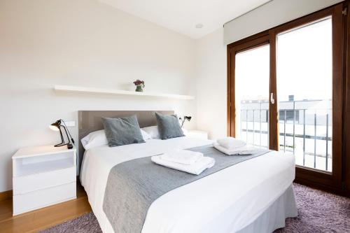a white bedroom with a large bed and a window at Jaizkibel by Basquelidays in Hondarribia