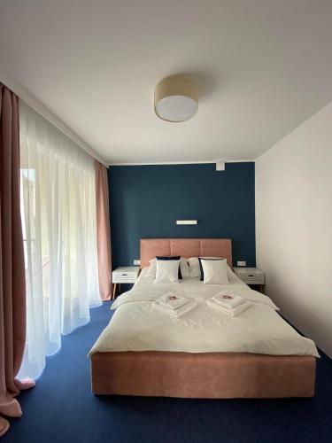 a bedroom with a large bed with a blue wall at Apartamenty Mistral in Jastarnia