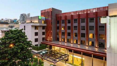 a building with a christmas tree in front of it at Holiday Inn Express Bangkok Sathorn by IHG in Bangkok