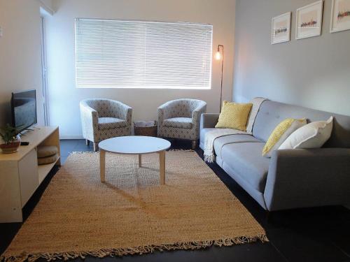sala de estar con sofá, 2 sillas y mesa en Overbeek 1 Bedroom 702 Apartment on Kloof Street, en Ciudad del Cabo