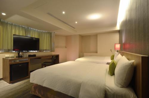 Una habitación de hotel con dos camas y un televisor de pantalla plana. en 欣欣時尚旅店松山站, en Taipéi