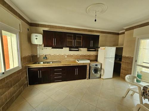 a kitchen with brown cabinets and a white refrigerator at Résidence Anouar in Tétouan