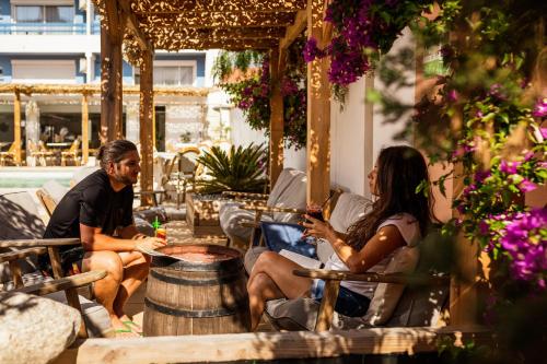Ein Mann und eine Frau, die auf einer Terrasse auf Stühlen sitzen in der Unterkunft Hôtel Les Sables - Urban Style - by Logis Hotels in Canet-en-Roussillon