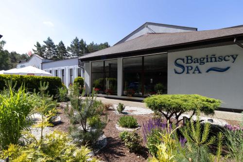 a building with a garden with plants in front of it at Bagińscy Spa in Pobierowo