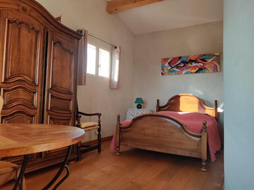 a bedroom with a bed and a wooden cabinet at LE CHARME DU VENTOUX in Crillon-le-Brave