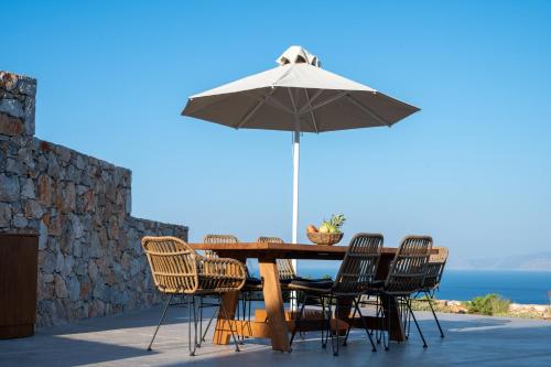 a wooden table with chairs and an umbrella at Horizon View Villa in Agios Nikolaos