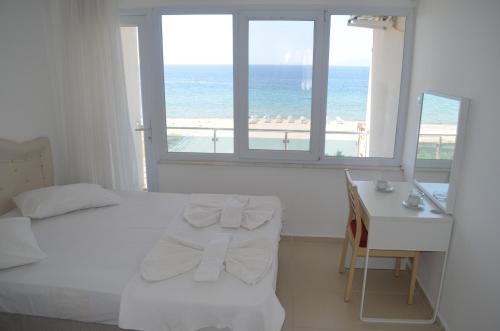 a bedroom with a bed and a desk with a view of the beach at Yasmin Hotel in Ayvalık