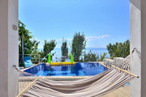 uma rede com piscina e o oceano ao fundo em Kuća za odmor u blizini Splita em Jesenice