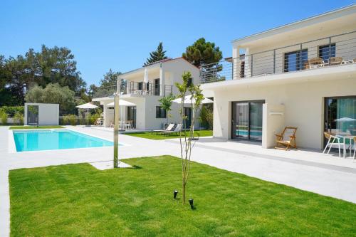 a villa with a swimming pool and a house at Filoxenia Luxury Apartments in Potos