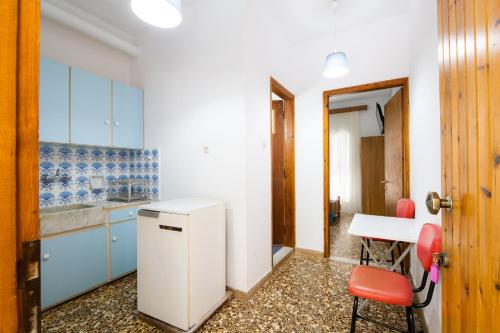 a kitchen with blue cabinets and a table and a red chair at Armonia Apartments in Kala Nera