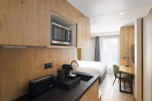 une chambre d'hôtel avec un lit et une cuisine avec un four micro-ondes dans l'établissement Residence Inn by Marriott Paris Didot Montparnasse, à Paris