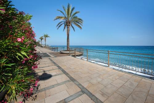 a pathway with a palm tree next to the ocean at Casa Cogoleto terrace and parking in Cogoleto
