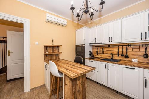 a kitchen with white cabinets and a wooden counter top at Rectorate Apartment in Plovdiv