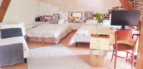 1 Schlafzimmer mit 2 Betten und einem Schreibtisch mit einem Computer in der Unterkunft Hameau de Leignoua in Le Saint