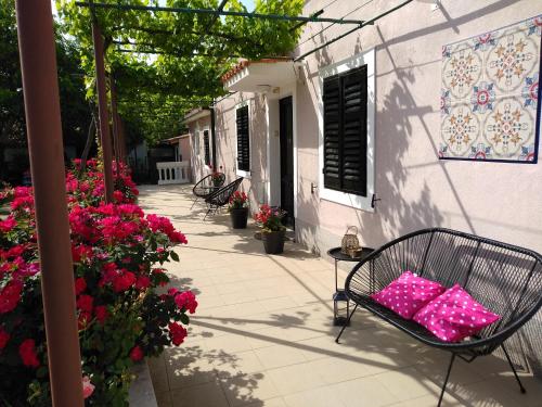 una silla con almohadas rosas en un patio con flores en Kuća Lilla, en Loborika