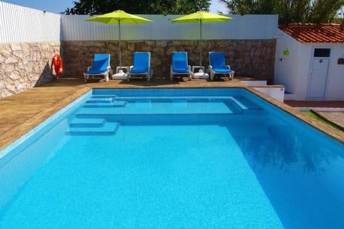 - une piscine avec des chaises et des parasols bleus dans l'établissement Hakuna Matata, à Cano