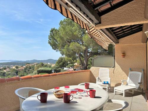 une table blanche et des chaises sur un balcon dans l'établissement Bormes-les-Mimosas: Appt climatisé, 5 couchages, parking, grande terrasse - FR-1-251-136, à Bormes-les-Mimosas