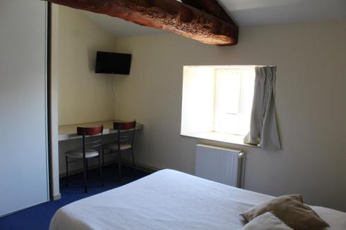 a bedroom with a bed and a desk and a window at Auberge de la Planèze in Talizat