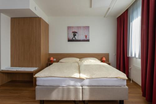 a bedroom with a bed and a red curtain at Hotel Sommerhaus Linz in Linz