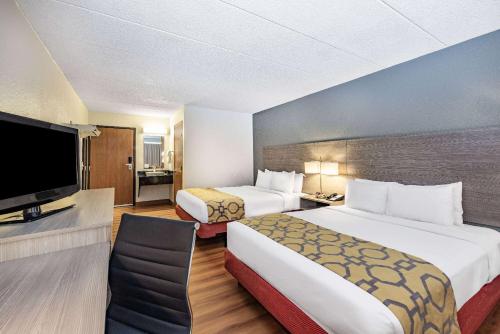a hotel room with two beds and a flat screen tv at Baymont by Wyndham Gillette in Gillette