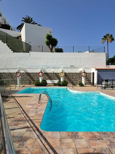 uma piscina com água azul em frente a um edifício em Chez Oti em Puerto Rico de Gran Canaria