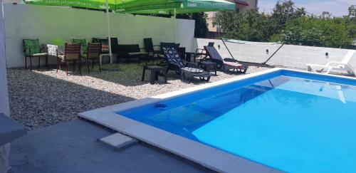 a blue swimming pool with chairs and an umbrella at Villa Hills in Mostar