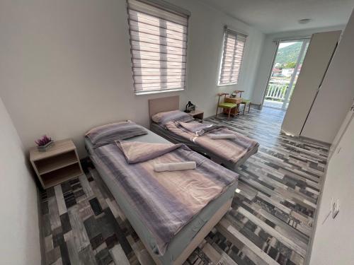 two beds in a room with two tables and windows at Villa Hills in Mostar