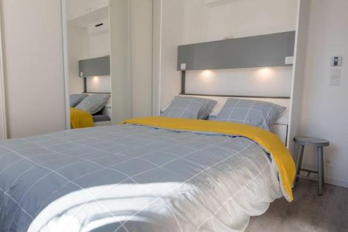 une chambre avec un lit avec une couverture jaune dessus dans l'établissement Studio Privé & Calme à S-Nazaire pr Parc Paysager, à Saint-Nazaire
