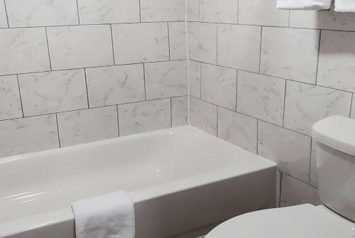 a white bathroom with a white tub and a toilet at Travelodge by Wyndham Livonia Canton Novi Detroit Area in Livonia