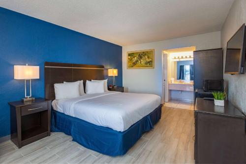 ein Schlafzimmer mit einem großen Bett mit blauer Wand in der Unterkunft Developer Inn Orlando North, a Baymont by Wyndham in Orlando