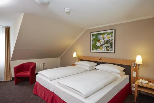 ein Hotelzimmer mit einem Bett und einem roten Stuhl in der Unterkunft H+ Hotel & SPA Friedrichroda in Friedrichroda