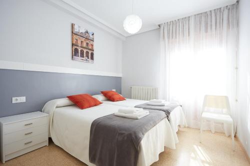 a white bedroom with two beds and a chair at Apartamento Turístico VIANA II in Viana