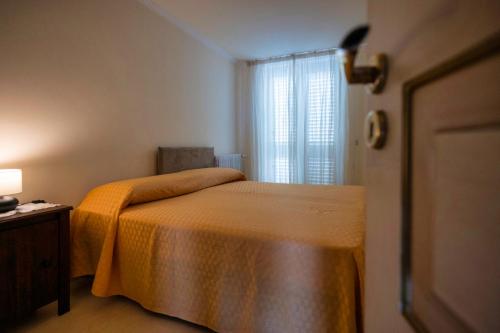 a bedroom with a bed with an orange bedspread and a window at Atticus Apartment in Giardini Naxos