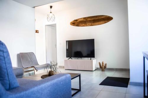 a living room with a tv and a blue chair at Renovated T6 house with garden near transport in Villenave-dʼOrnon